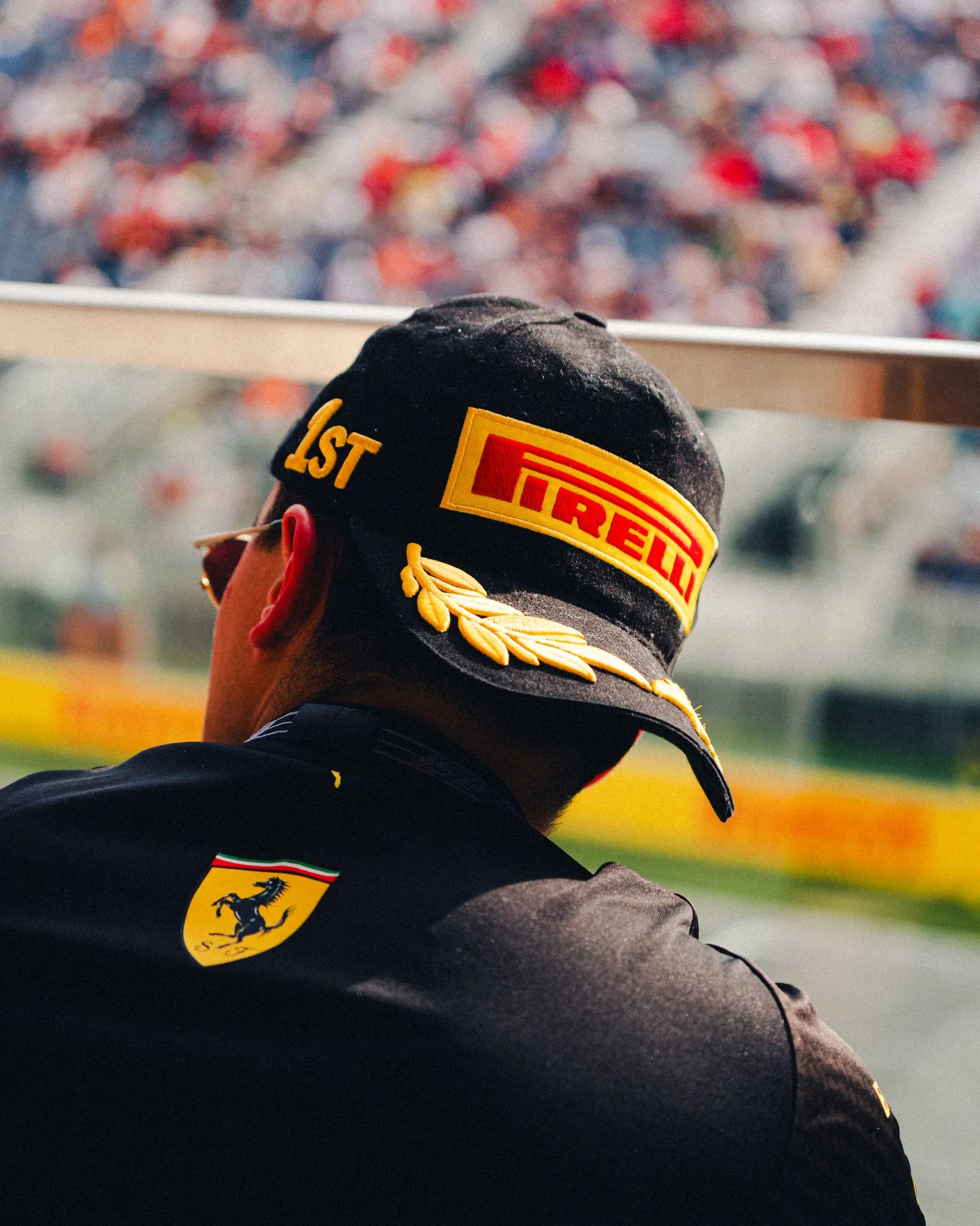 Spectator in a Pirelli podium cap watching from the grandstand