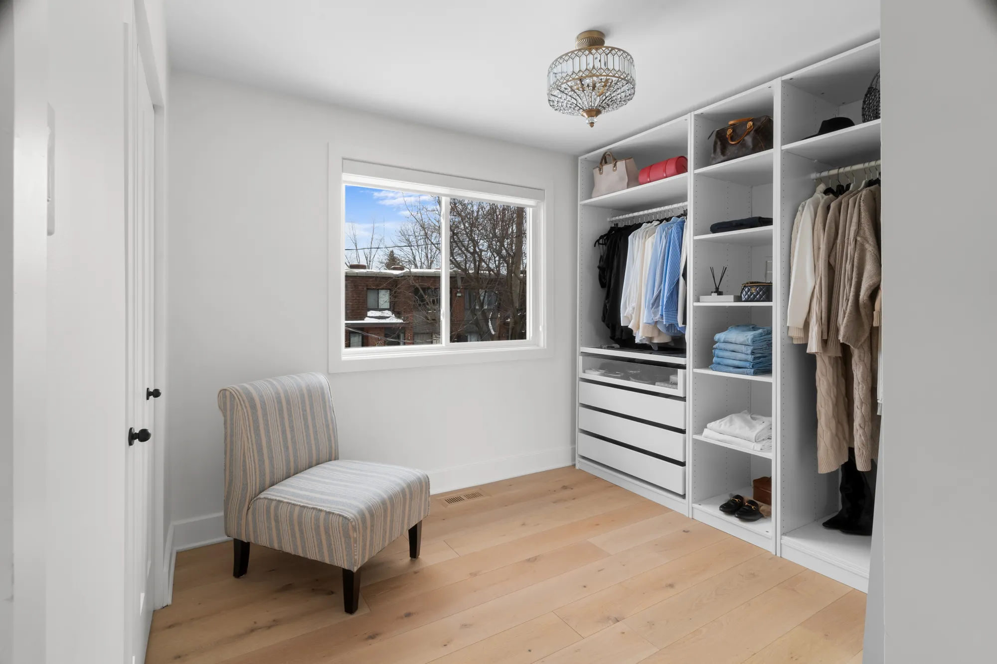 Walk-in closet with chandelier and reading chair
