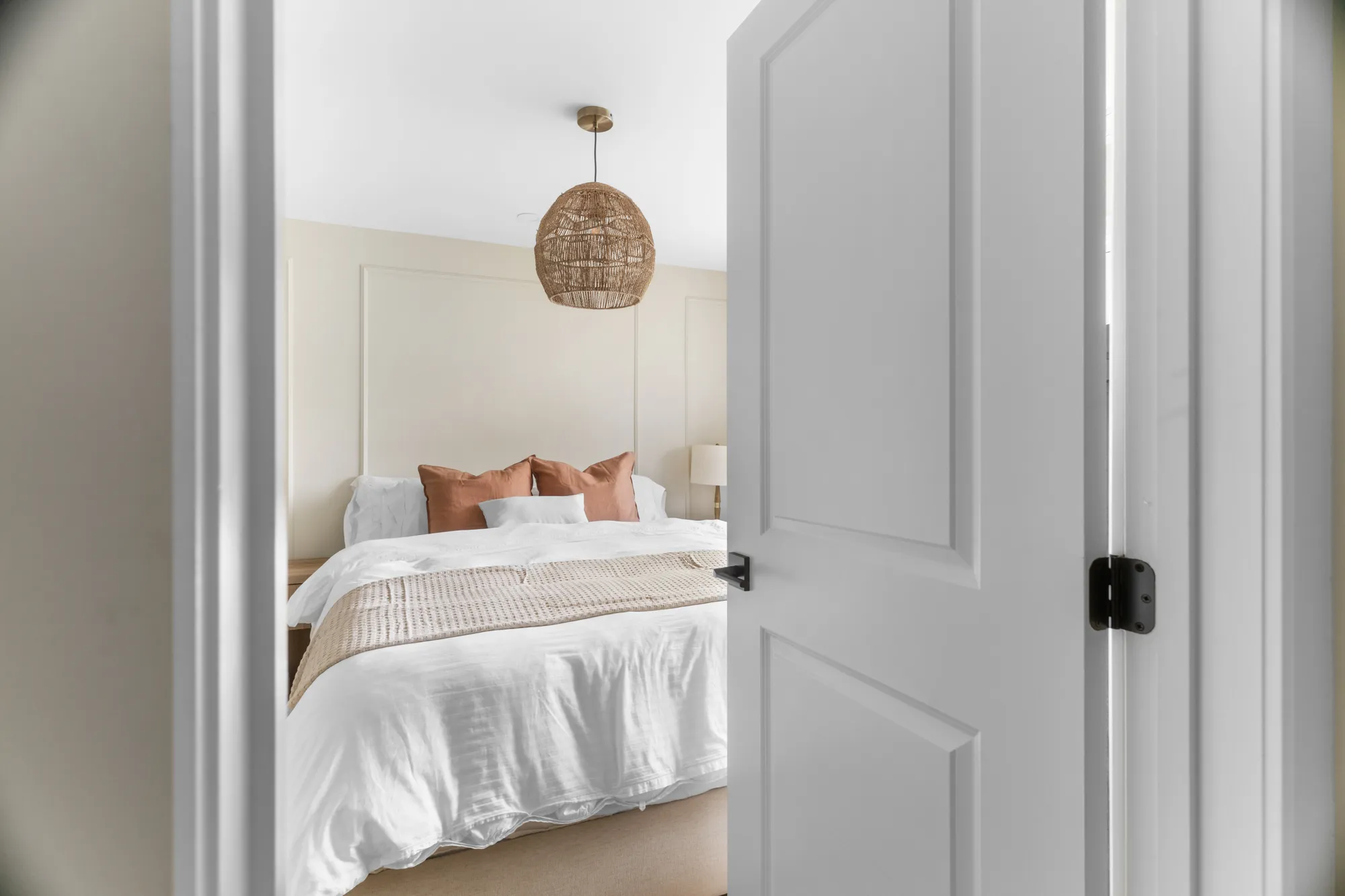 Bedroom seen through the doorway, rattan pendant above the bed