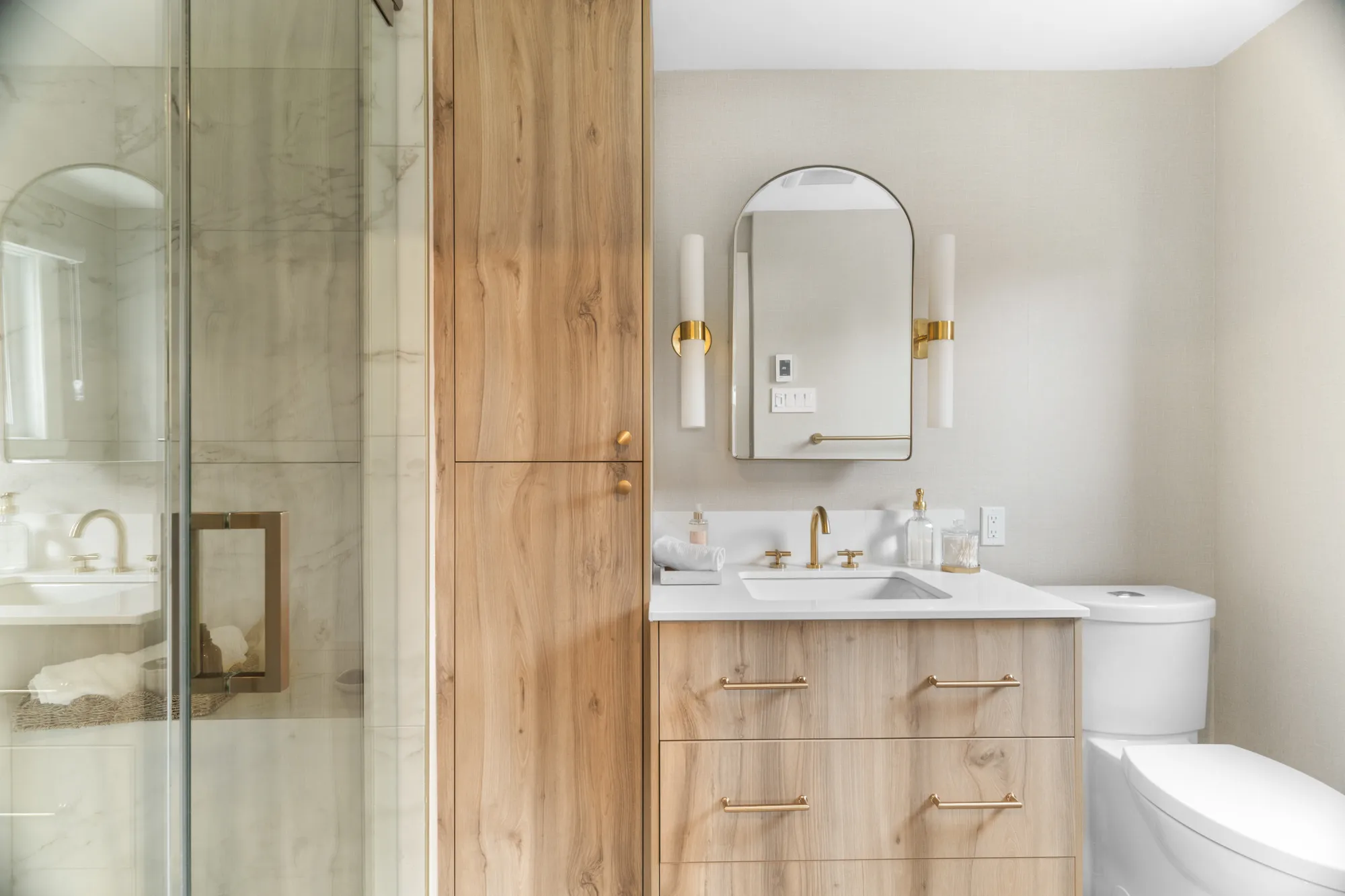 Bathroom vanity with arched mirror and white-oak millwork